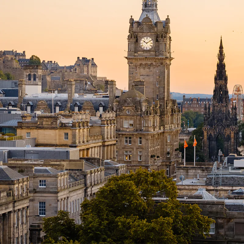 Edinburgh skyline with historic buildings, castle, and Scott Monument at sunset.