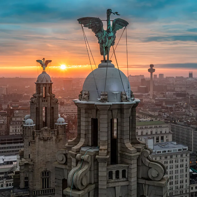 Liverpool Liver Building and waterfront cityscape at dawn under dramatic skies.