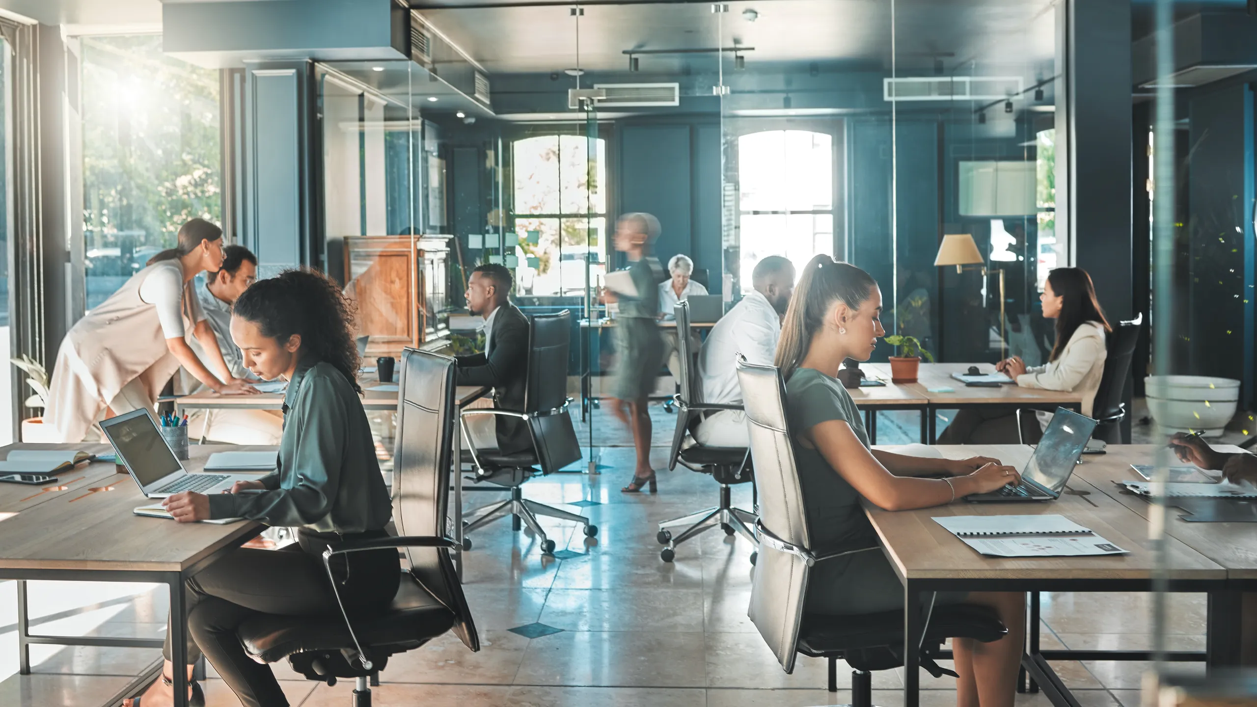 Contemporary co-working office environment with business teams using laptops and digital tools.