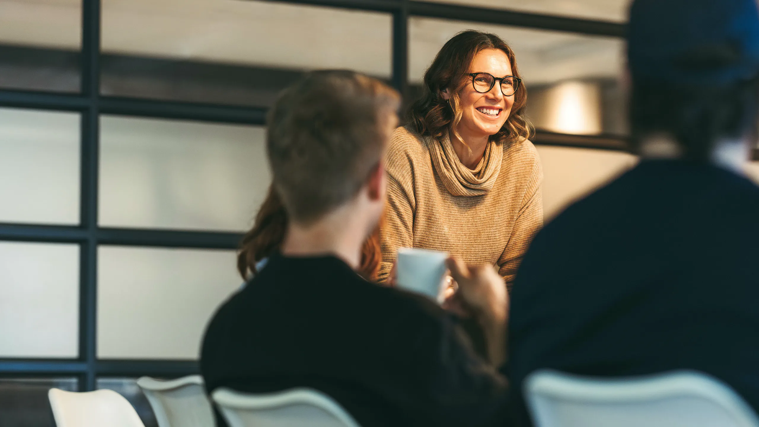 Professional woman discussing business ideas with team members in a modern office setting.