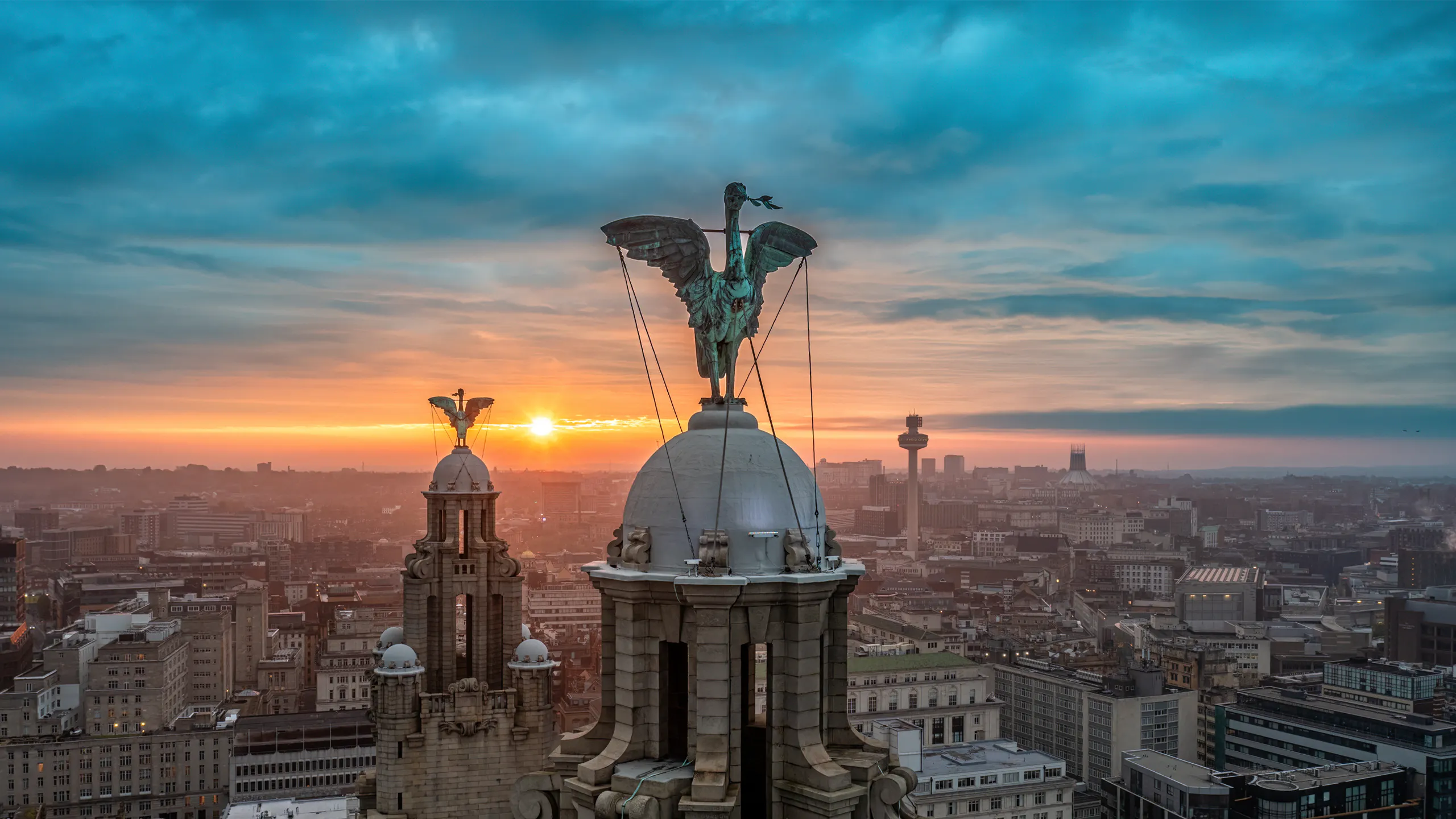 Liverpool Liver Building and waterfront cityscape at dawn under dramatic skies.